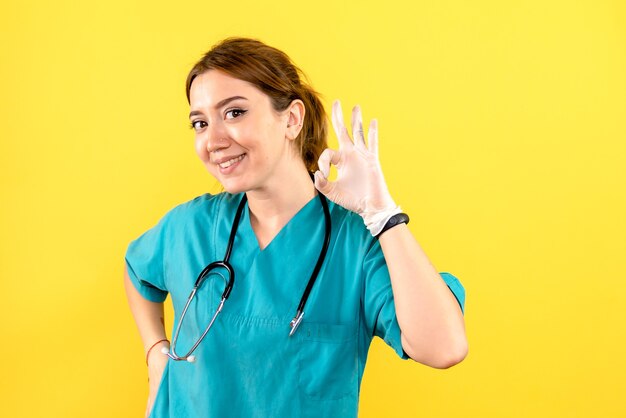 Vista frontale del veterinario femminile in posa e sorridente sulla parete gialla