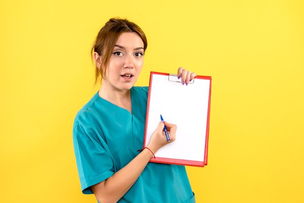 Vista frontale del veterinario femminile scrivere note sulla parete gialla