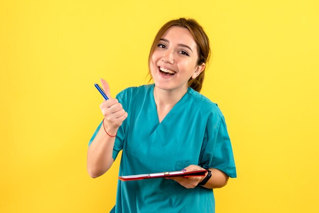 Vista frontale del veterinario femminile scrivere note sulla parete gialla