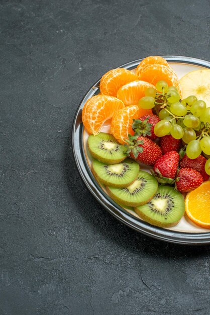 Vista frontale deliziosa composizione di frutta fresca affettata e frutta dolce su sfondo scuro frutta fresca e matura per la dieta salutare