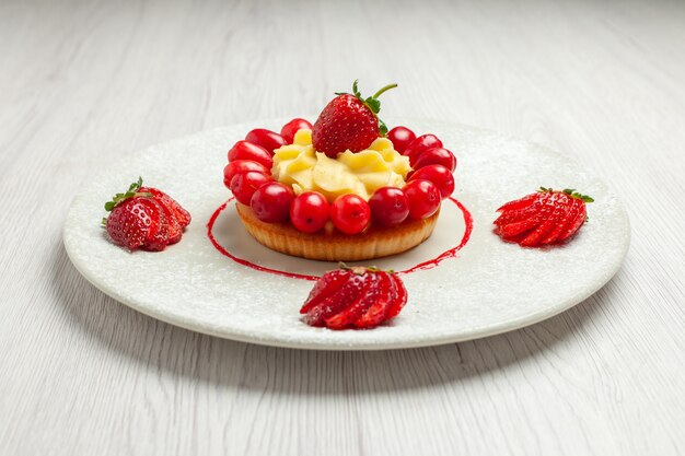 Vista frontale deliziosa piccola torta con frutta all'interno del piatto sulla frutta dessert torta bianca scrivania