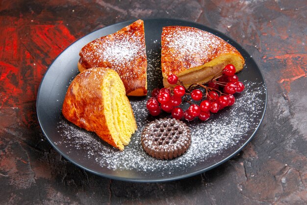 Vista frontale deliziosa torta a fette con bacche rosse sul pavimento scuro