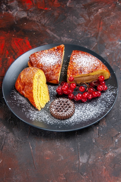 Vista frontale deliziosa torta a fette con bacche rosse sul tavolo scuro