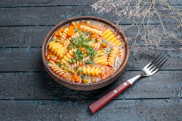 Vista frontale deliziosa zuppa di pasta da pasta italiana a spirale con verdure su piatto da pranzo rustico scuro da scrivania salsa di zuppa di pasta italiana