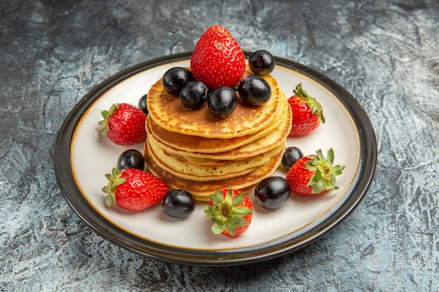 Vista frontale deliziose frittelle con frutta e bacche sul dessert torta di frutta piano scuro