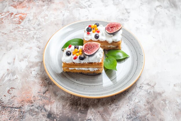 Vista frontale deliziose torte cremose con frutta fresca su sfondo chiaro