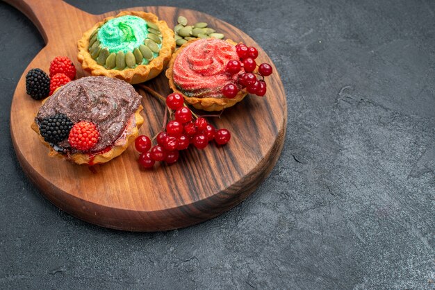 Vista frontale deliziose torte cremose con frutti di bosco su sfondo scuro