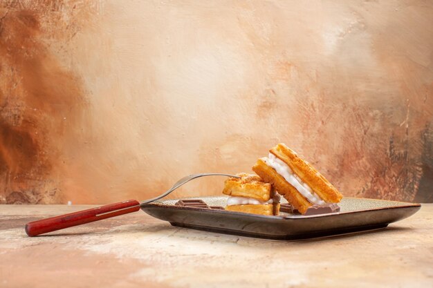 Vista frontale deliziose torte di waffle con barrette di cioccolato sullo sfondo marrone