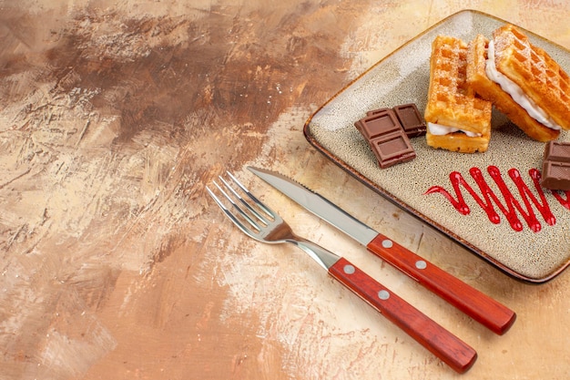 Vista frontale deliziose torte di waffle con barrette di cioccolato sullo sfondo marrone