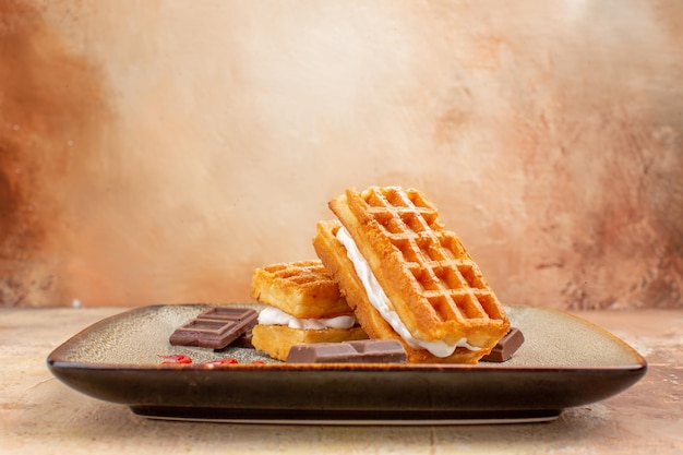 Vista frontale deliziose torte di waffle con barrette di cioccolato sullo sfondo marrone