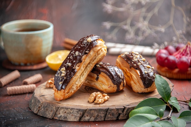 Vista frontale deliziosi bignè al cioccolato su sfondo scuro