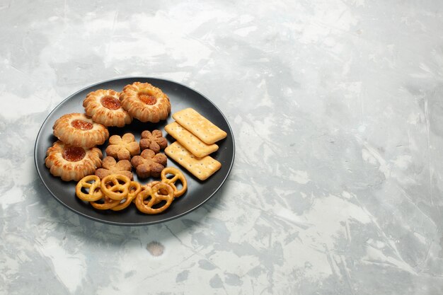 Vista frontale deliziosi biscotti con cracker e patatine all'interno del piatto sulla scrivania bianco chiaro