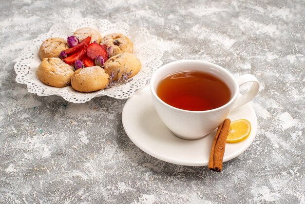 Vista frontale deliziosi biscotti di sabbia con fragole fresche e tazza di tè su uno spazio bianco