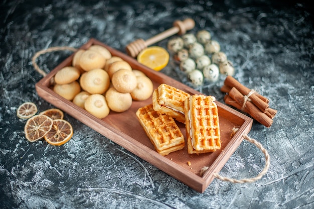 Vista frontale deliziosi biscotti dolci con piccole torte su torta di noci di biscotto di zucchero torta di colore grigio dolce