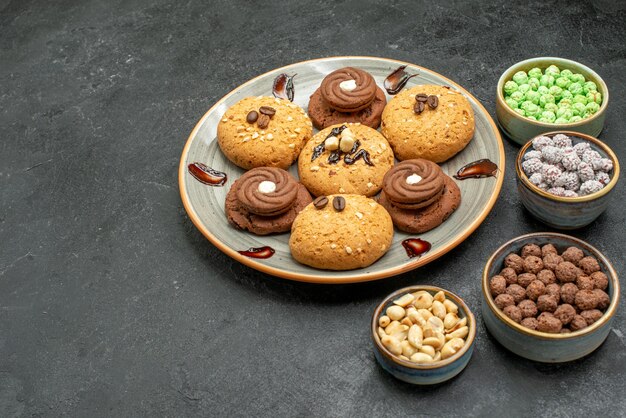 Vista frontale deliziosi biscotti dolci deliziosi dolci per il tè su uno spazio grigio