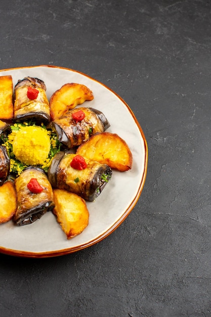 Vista frontale deliziosi involtini di melanzane piatto cotto con patate al forno sullo sfondo scuro piatto da pasto che cucina il cibo cuocere le patate fritte