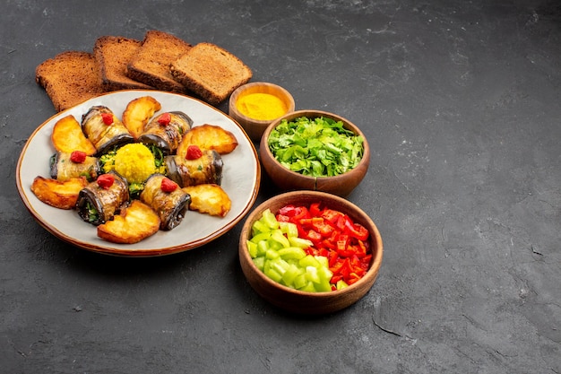 Vista frontale deliziosi involtini di melanzane piatto cucinato con patate al forno e pane su fondo scuro piatto che cucina cibo fritto di patate al forno