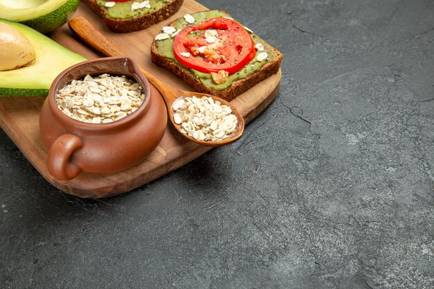 Vista frontale deliziosi panini con avocado e pomodori rossi su sfondo grigio pranzo spuntino pasto hamburger panino