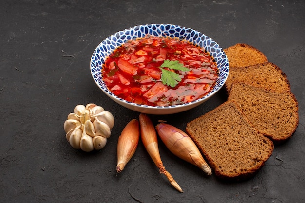 Vista frontale delizioso borsch con pagnotte di pane scuro su spazio buio