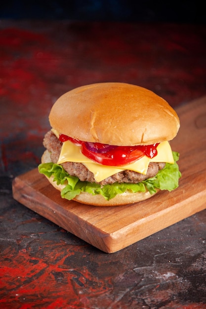 Vista frontale delizioso cheeseburger con pomodori a base di carne e insalata verde su sfondo scuro sandwich fast-food pasto spuntino patatine fritte piatto