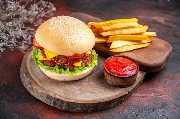 Vista frontale delizioso hamburger di carne con patatine fritte su sfondo scuro