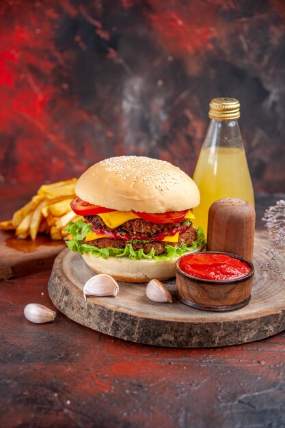 Vista frontale delizioso hamburger di carne con patatine fritte sul pavimento scuro