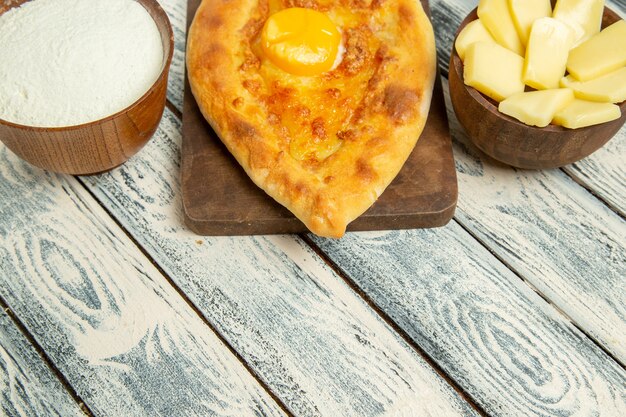 Vista frontale delizioso pane all'uovo cotto con farina e formaggio su una scrivania rustica