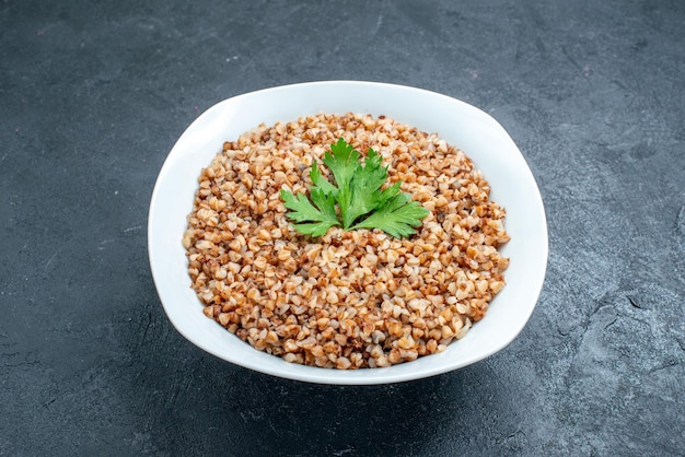 Vista frontale delizioso pasto utile di grano saraceno cotto all'interno del piatto sullo spazio buio
