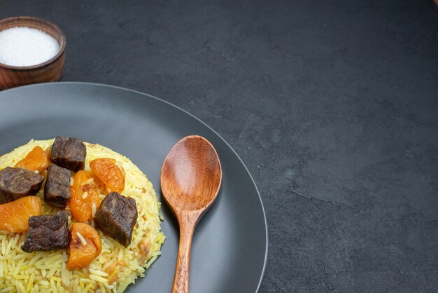 Vista frontale delizioso riso cotto pilaf con fette di carne sale sulla superficie scura