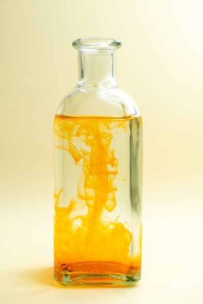 Vista frontale dell'acqua in lattina con vernice arancione su disegno fotografico a colori della scrivania bianca