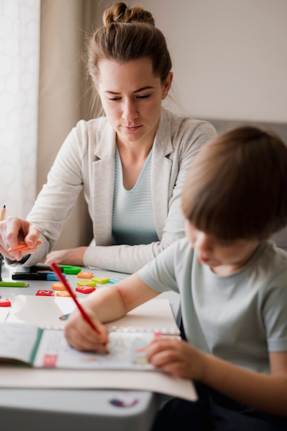 Vista frontale dell'insegnante femminile che insegna al bambino a casa