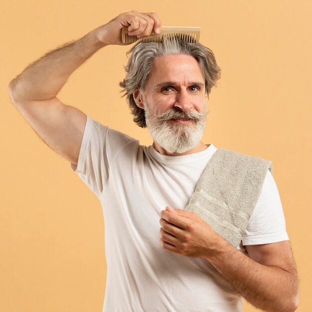 Vista frontale dell'uomo anziano con la barba che si pettina i capelli