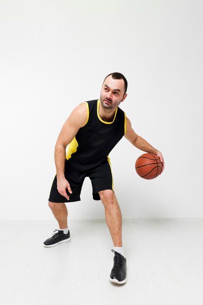 Vista frontale dell'uomo che gioca a basket in scarpe da ginnastica