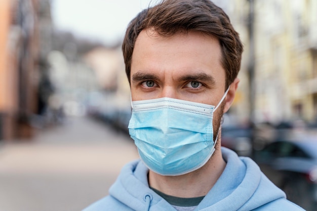 Vista frontale dell'uomo che indossa la mascherina medica nella città