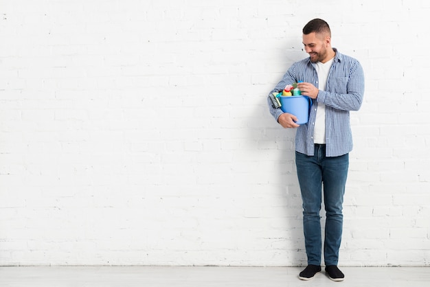 Vista frontale dell'uomo che posa con i prodotti di pulizia e lo spazio della copia