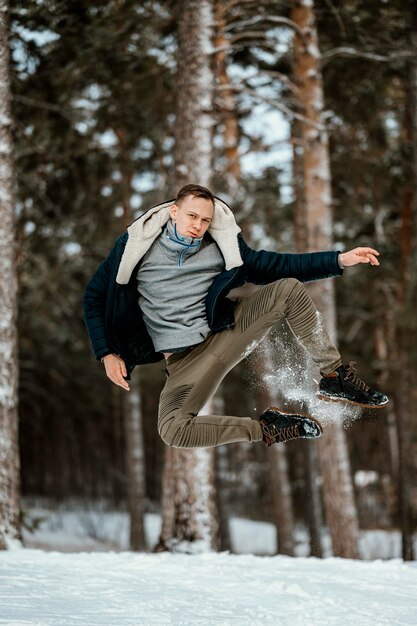 Vista frontale dell'uomo che salta all'aperto nella natura durante l'inverno