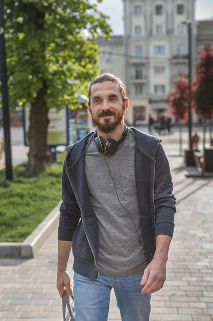 Vista frontale dell'uomo con le cuffie in città