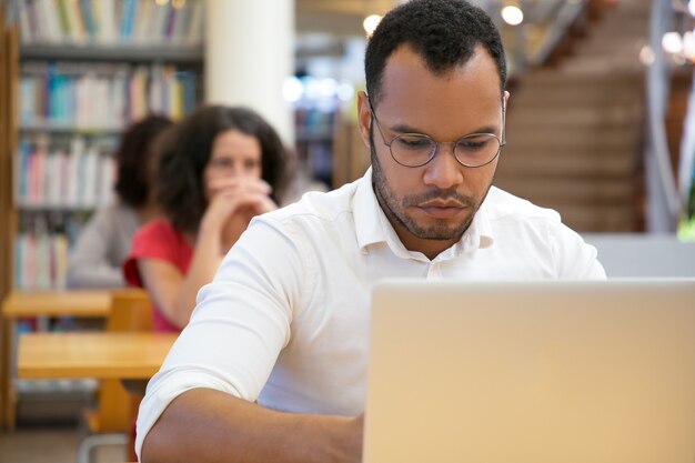 Vista frontale dell'uomo concentrato che scrive sul computer portatile