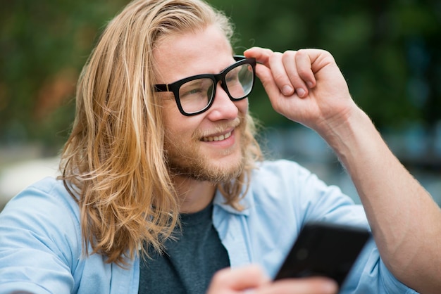 Vista frontale dell'uomo di smiley all'aperto con lo smartphone