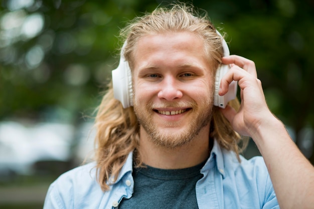 Vista frontale dell'uomo di smiley con le cuffie all'aperto