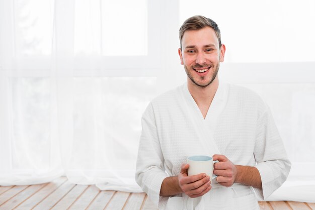 Vista frontale dell'uomo in accappatoio che tiene tazza