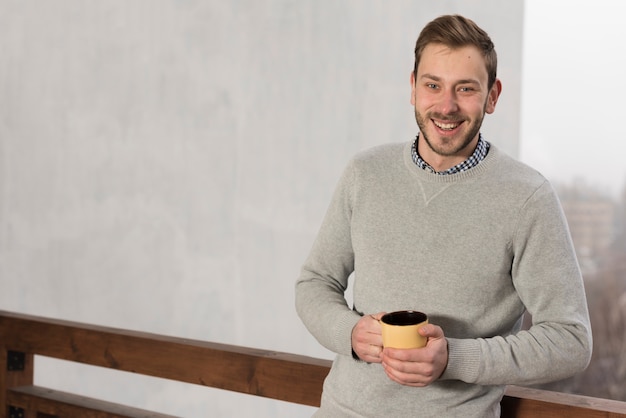 Vista frontale dell'uomo in maglione che tiene tazza in mano