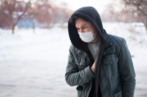 Vista frontale dell'uomo malato che indossa una maschera medica