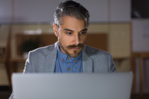 Vista frontale dell'uomo messo a fuoco che esamina computer portatile