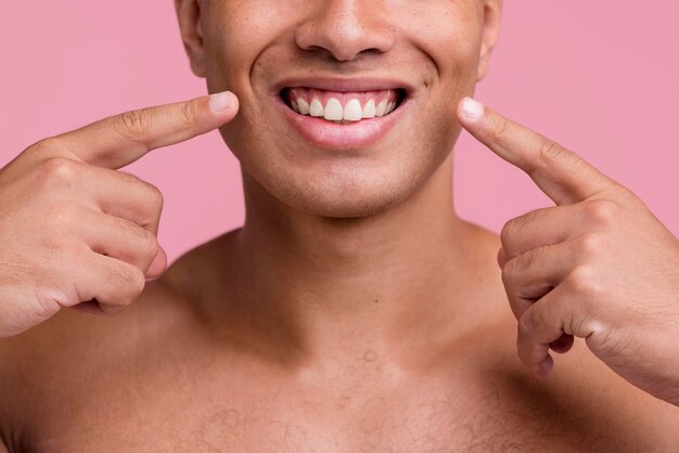 Vista frontale dell'uomo senza camicia che indica il suo bel sorriso