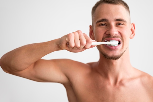 Vista frontale dell'uomo senza camicia che pulisce i suoi denti