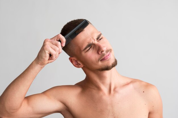 Vista frontale dell'uomo senza camicia che usando un pettine