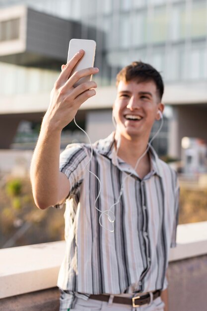 Vista frontale dell'uomo sorridente che ha una videochiamata all'aperto