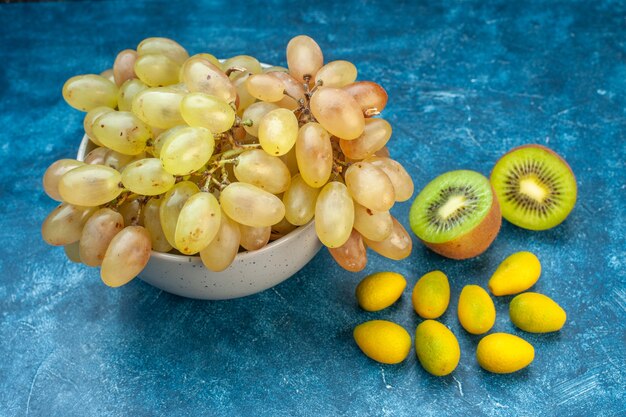 Vista frontale dell'uva fresca all'interno del piatto su una foto di succo di frutta di colore maturo blu