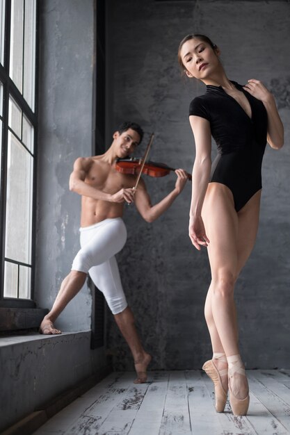 Vista frontale della ballerina in body e musicista maschio